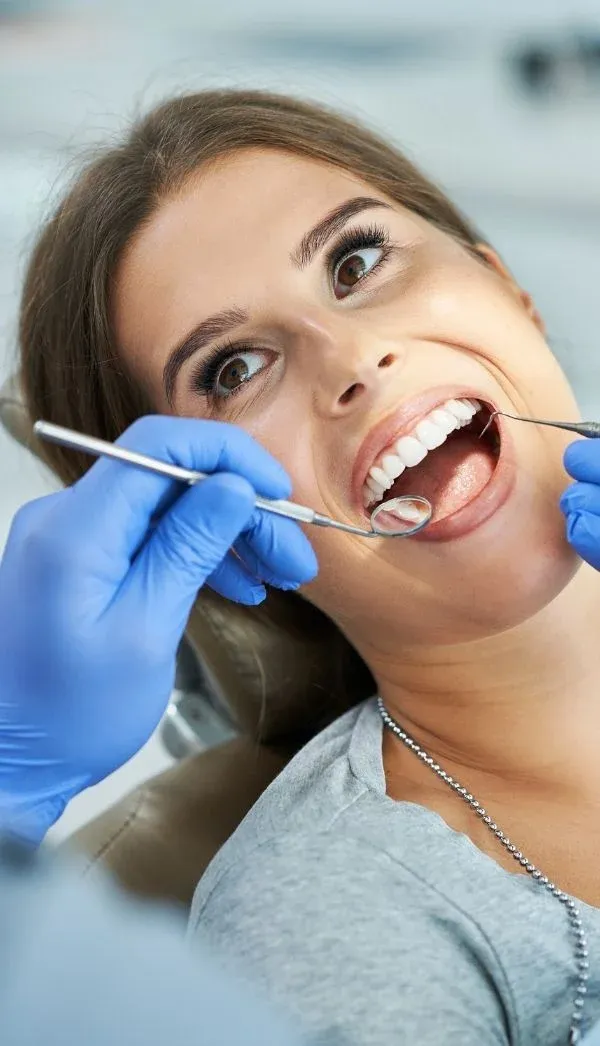 A patient having their teeth examined with a dental mirror and probe
