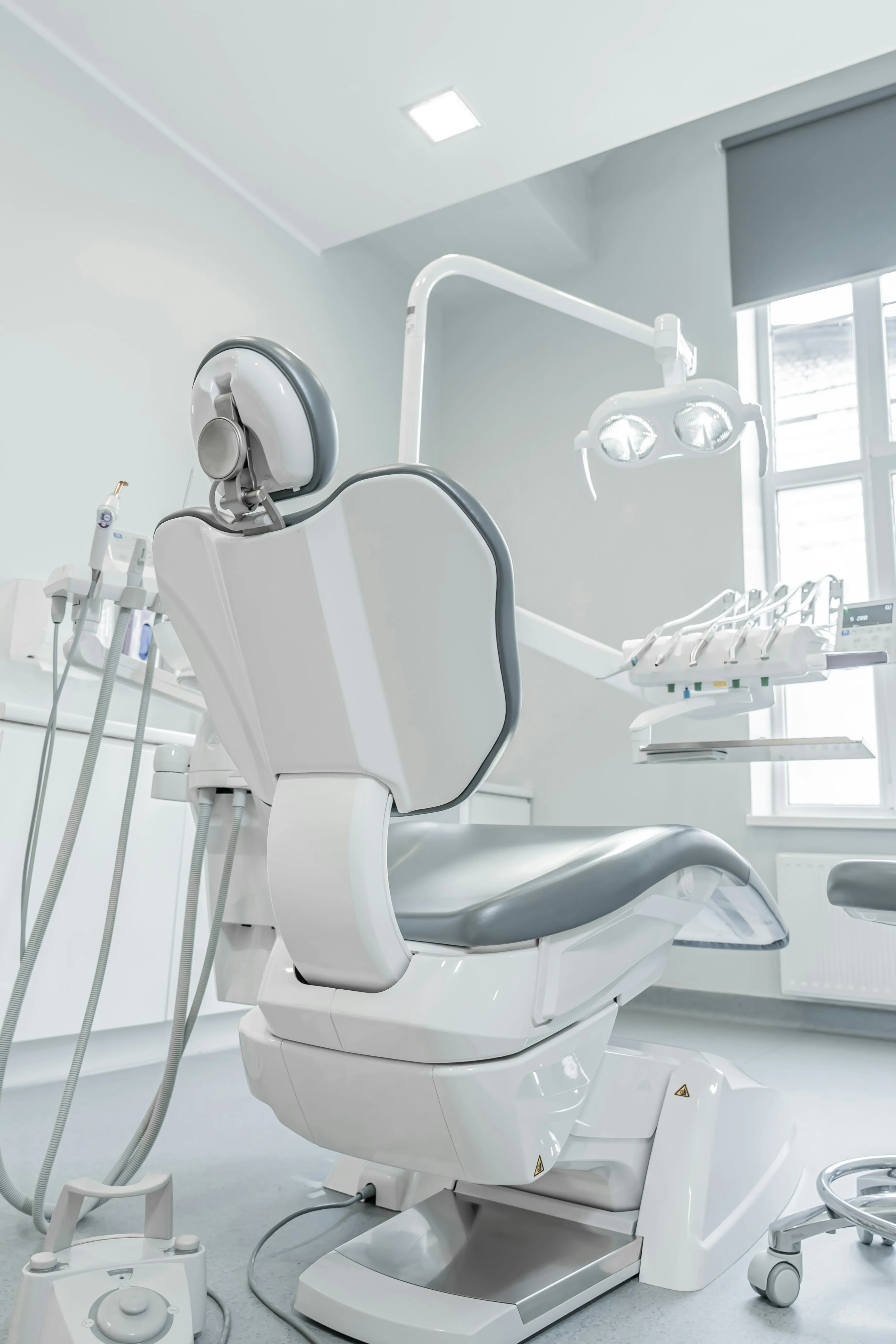 A clean dental chair beneath an overhead examination light